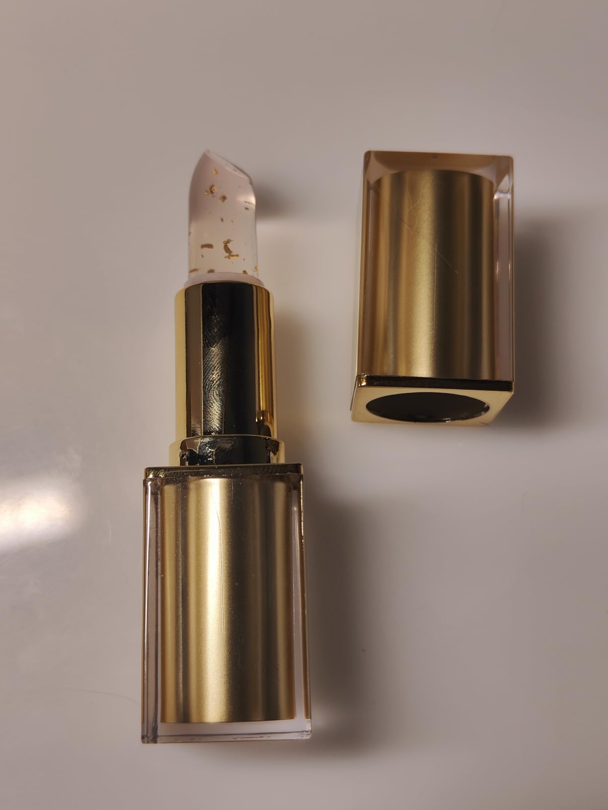 Gold lipstick on a soft pink background